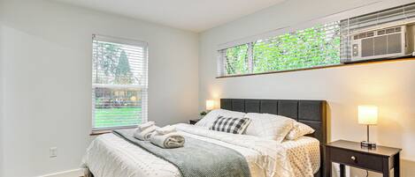 A neatly arranged bedroom with a bed, bedside table, and a window with blinds.