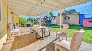 Une terrasse couverte avec un sol en pierre, une table de pique-nique et deux chaises.
