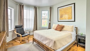 A bedroom with a large bed, a chair, a nightstand, and a map on the wall.