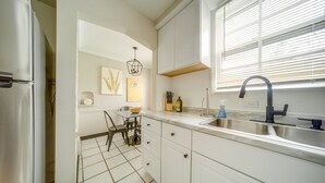A kitchen with white cabinets, a stainless steel sink, and a tiled floor. - Vacation Rental Near Cleveland, Ohio: 6 Mi Away! (University Heights)
