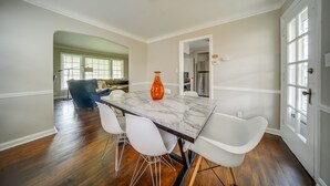 A dining area with a marble table, white chairs, and a vase. - Vacation Rental Near Cleveland, Ohio: 6 Mi Away! (University Heights)