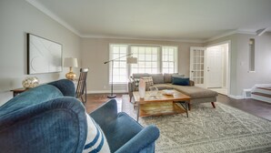 A living room with a blue armchair, a beige sofa, and a patterned rug. - Vacation Rental Near Cleveland, Ohio: 6 Mi Away! (University Heights)