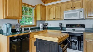 A kitchen with wooden cabinets, a microwave, a stove, a dishwasher, and a coffee maker. - Mtn-view Escape w/ Hot Tub, 9 Mi to Skiing! (Maggie Valley)