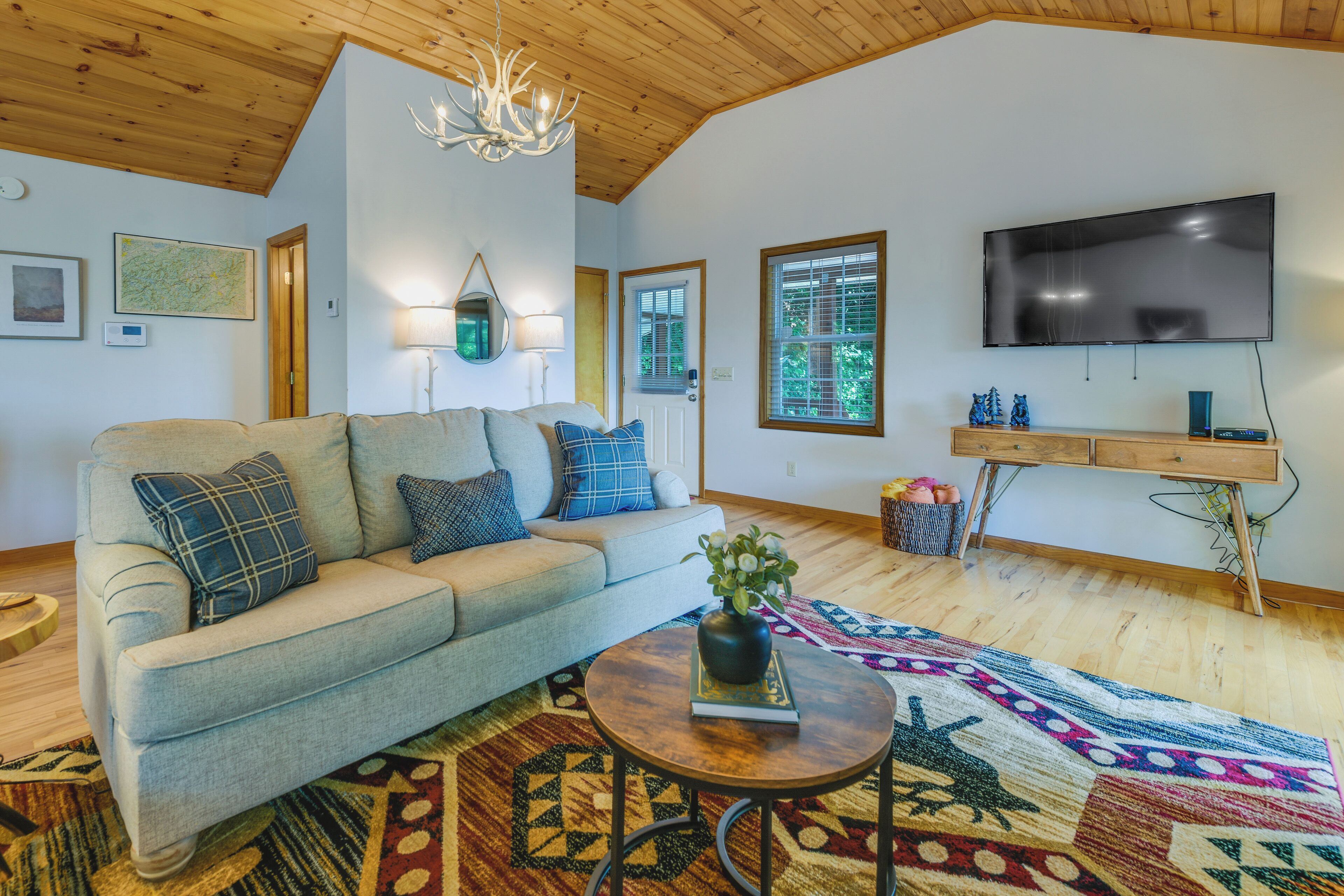 A cozy living room with a sofa, a coffee table, a TV, and a wooden ceiling.