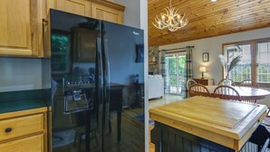 A modern kitchen with a black refrigerator, wooden cabinets, and a dining area with a table and chairs. - Mtn-view Escape w/ Hot Tub, 9 Mi to Skiing! (Maggie Valley)