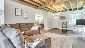 A spacious living area with a brown sectional sofa, a wooden ceiling, and a kitchen in the background. - Large Historic Home in Pennsylvania Dutch Country! (Coatesville)