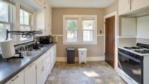 A kitchen with a stove, sink, and two trash cans.