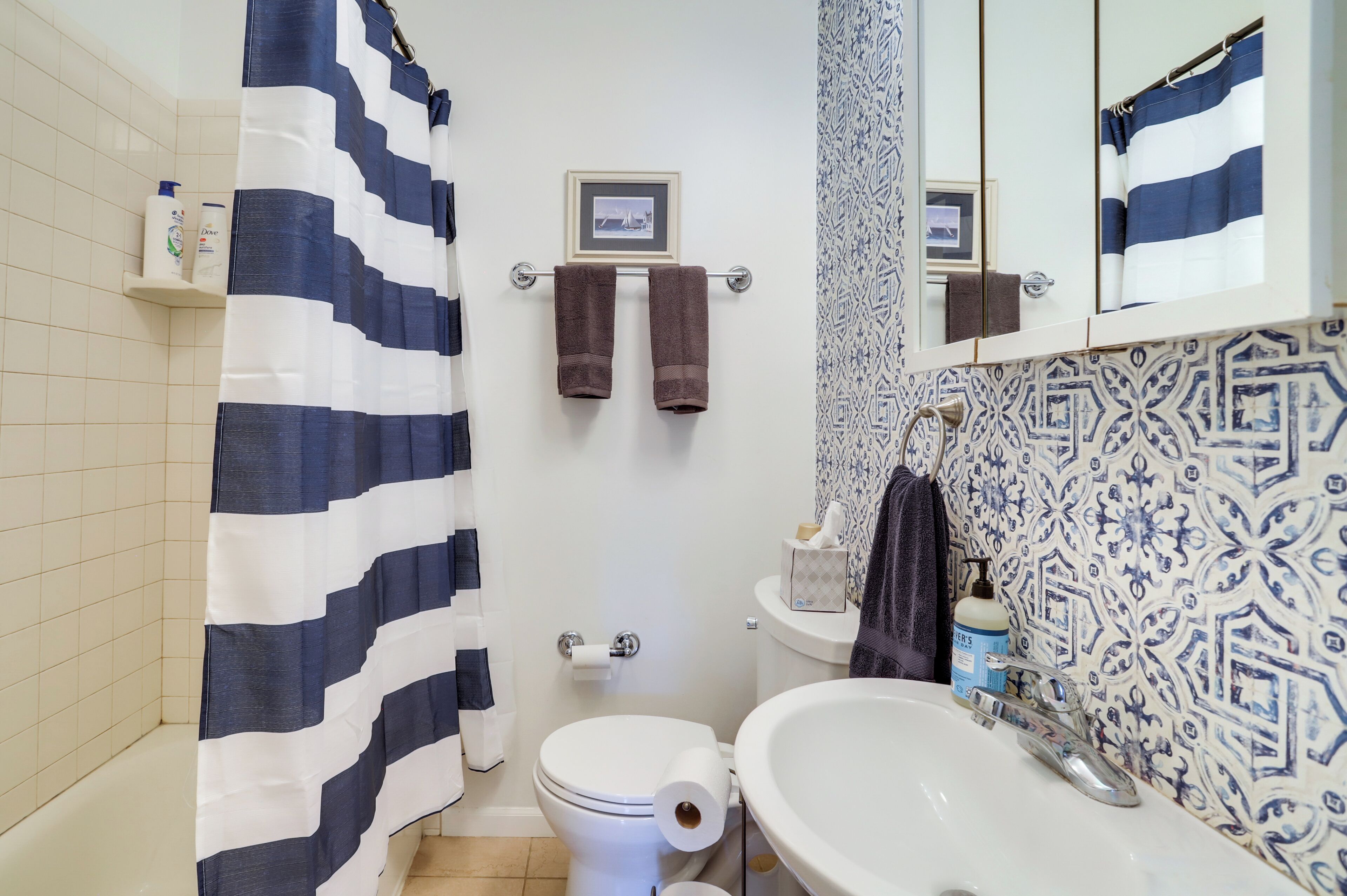 Une salle de bain avec un rideau de douche à rayures, des toilettes, un lavabo et un miroir.