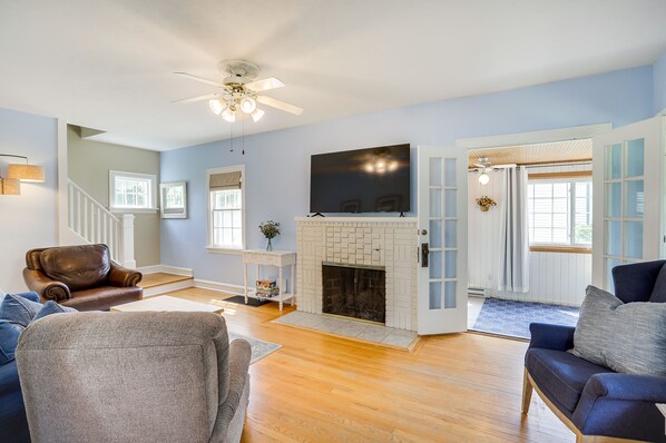 A living room with a fireplace, wooden flooring, and a ceiling fan.