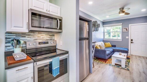 A modern kitchen with white cabinets, stainless steel appliances, and a blue-towel oven. - Cozy Melbourne Hideaway Near Beaches, Downtown! (Melbourne)