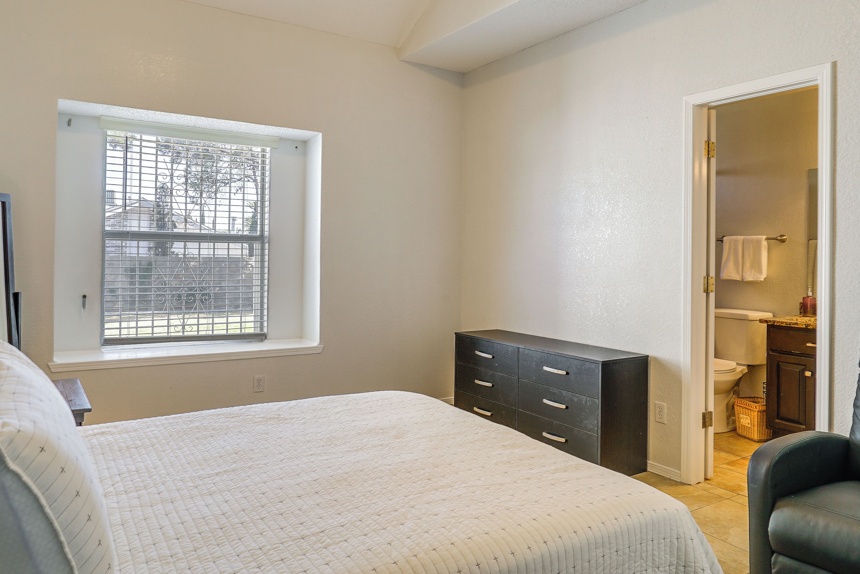 Une chambre à coucher avec un lit, une commode, une fenêtre et une vue sur l’extérieur.