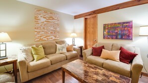 A living room with two beige sofas, a wooden coffee table, and a wooden ceiling beam. - Tasteful Galena Townhome w/ Community Amenities (Galena)