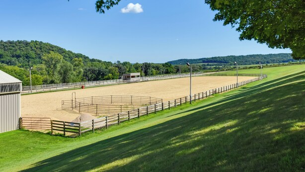 A fenced equestrian arena with a sandy surface, surrounded by green fields and trees. - Tasteful Galena Townhome w/ Community Amenities (Galena)