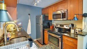 A modern kitchen with stainless steel appliances, wooden cabinets, granite countertops, and a built-in oven. - Tasteful Galena Townhome w/ Community Amenities (Galena)
