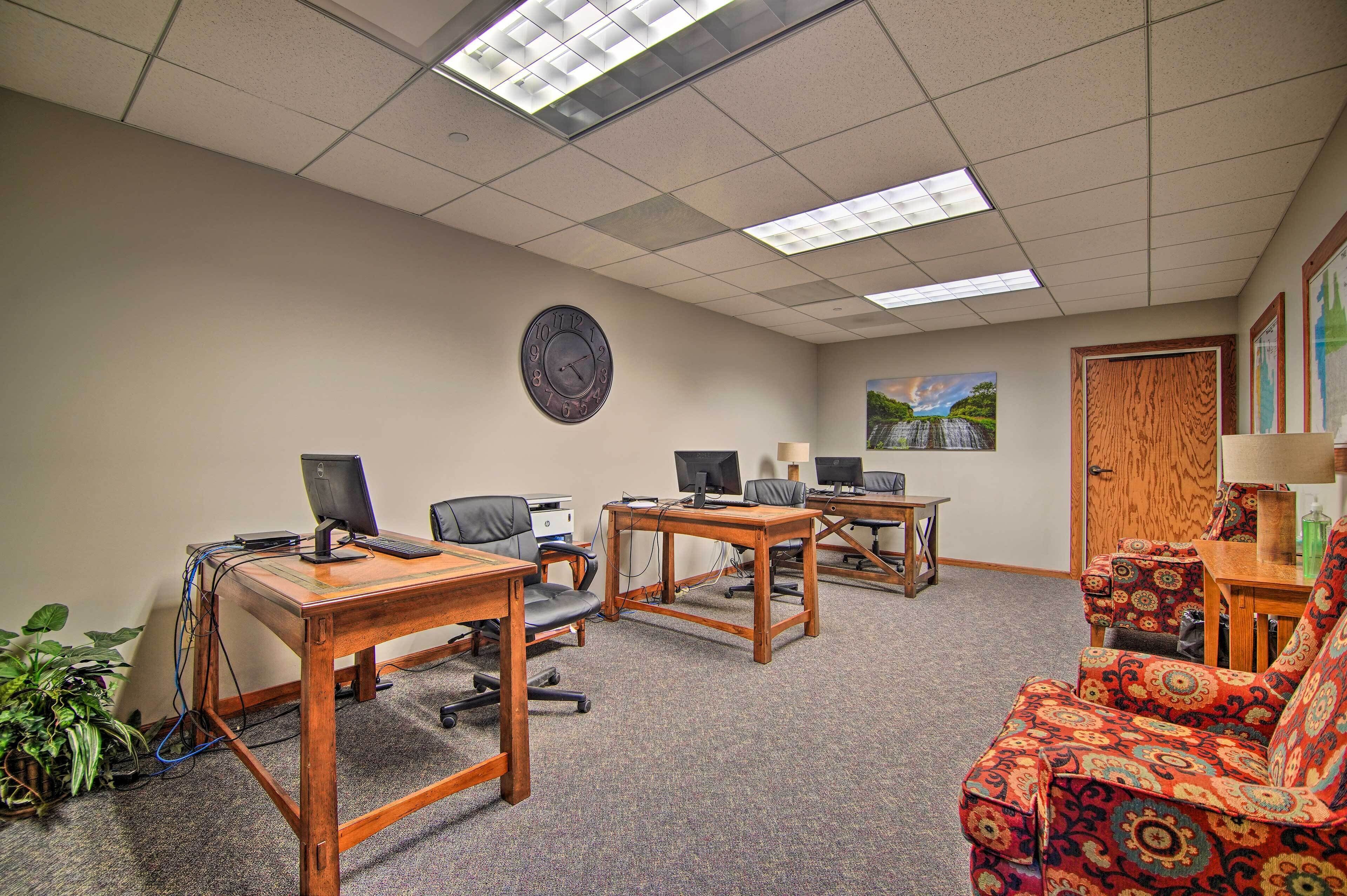 A conference room with three desks, two chairs, a clock, and a painting on the wall.