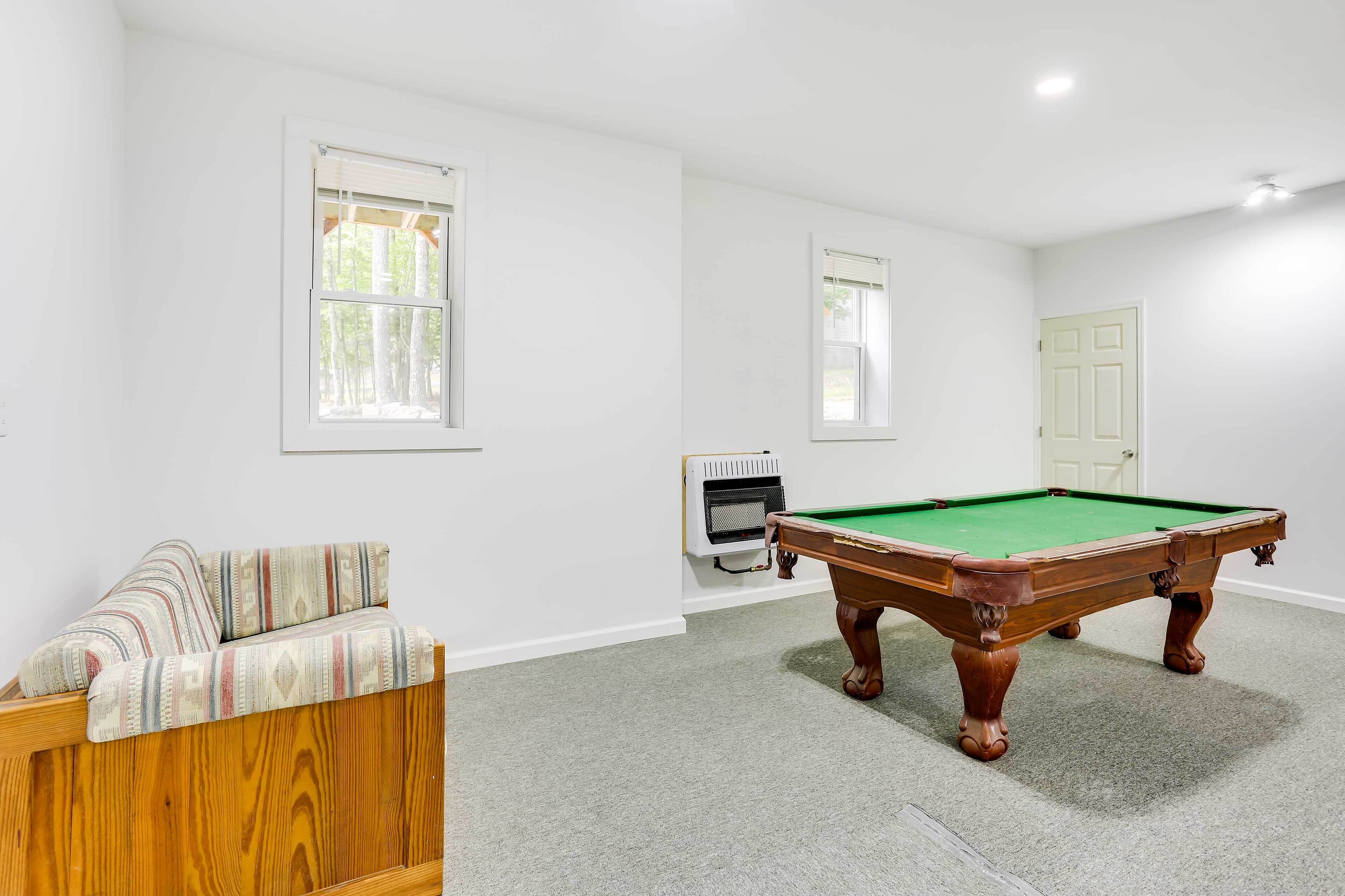 A room with a pool table, a sofa, and a door.