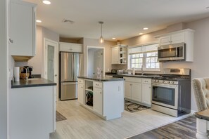 Una cocina moderna con armarios blancos, electrodomésticos de acero inoxidable y una isla central.