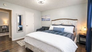 Une chambre à coucher avec un grand lit, une table de chevet, une chaise et un miroir.