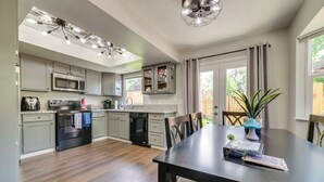 Une cuisine moderne avec des meubles gris, une cuisinière noire et un coin repas comprenant une table et des chaises.