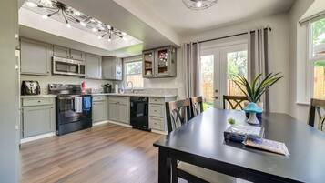 A modern kitchen with grey cabinets, a black stove, and a dining area with a table and chairs.