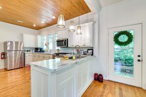 Una cocina moderna con gabinetes blancos, electrodomésticos de acero inoxidable y una isla de mármol.