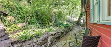 A stone pathway leading to a wooden house with a green door and a chair outside.