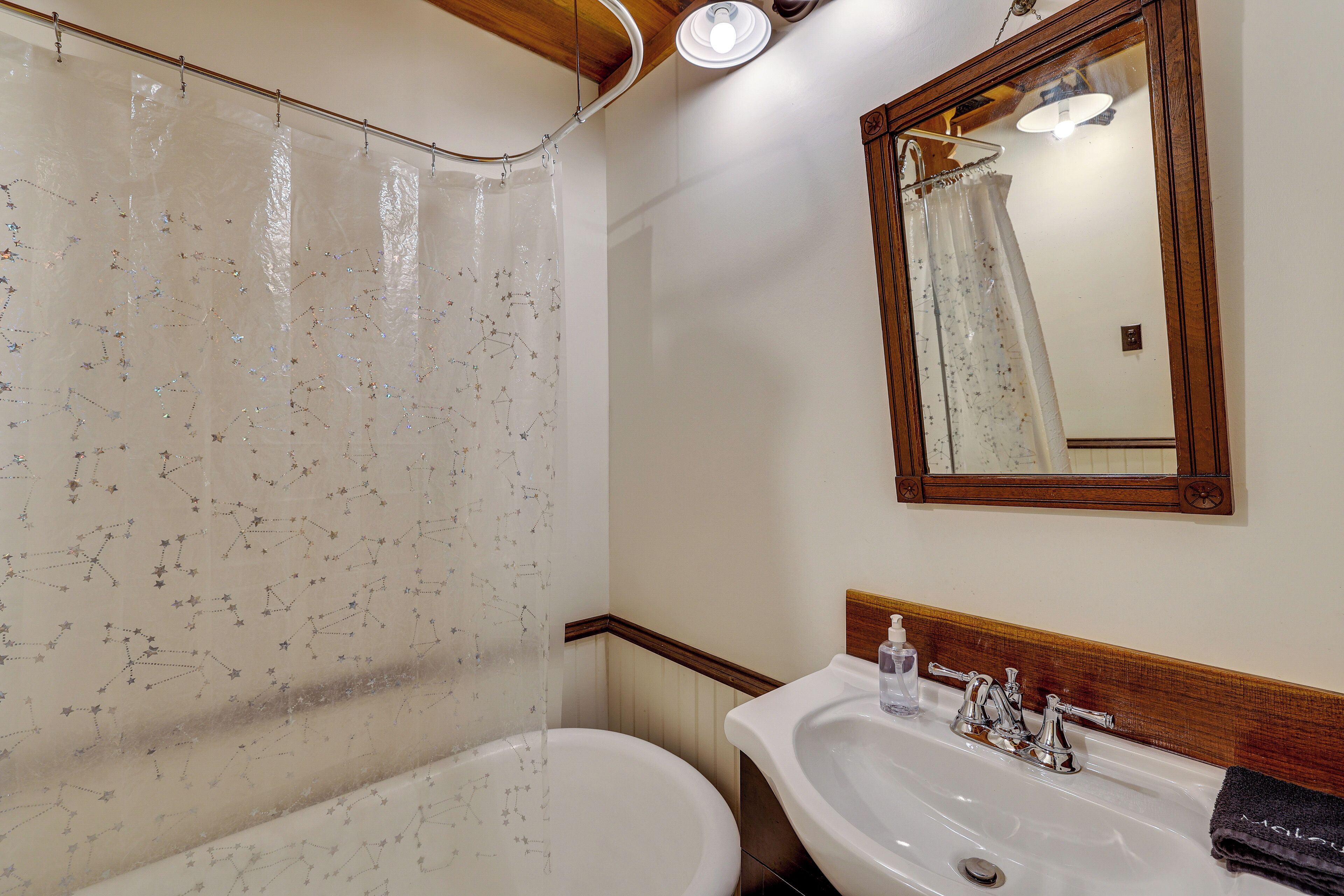 Un baño con cortina de ducha, bañera, lavabo y espejo.