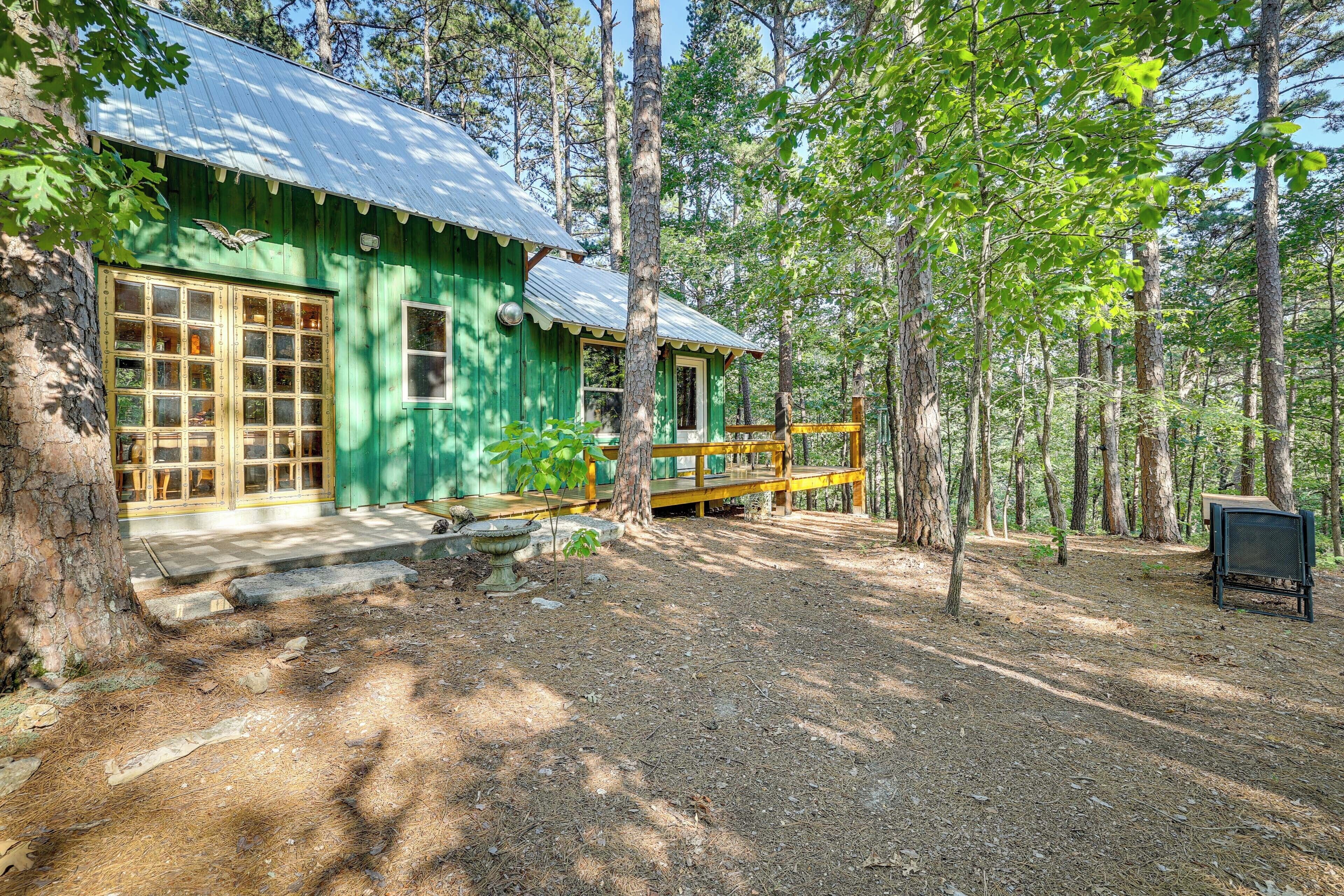 A rustic cabin with a metal roof, wooden deck, and a stone wall.
