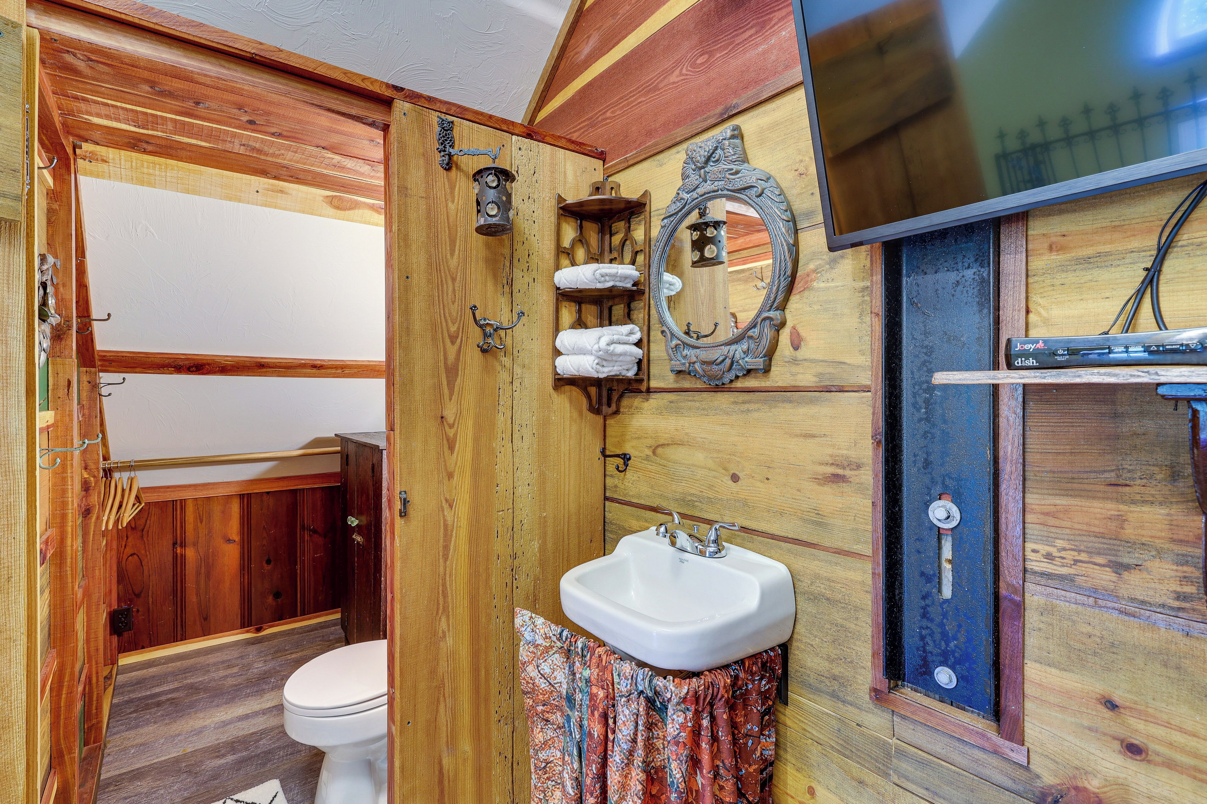 Un baño de madera con inodoro, lavabo y espejo.