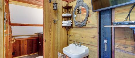 Un baño de madera con inodoro, lavabo y espejo.