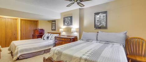 A bedroom with two single beds, a wooden wardrobe, a nightstand with a lamp, and a ceiling fan.