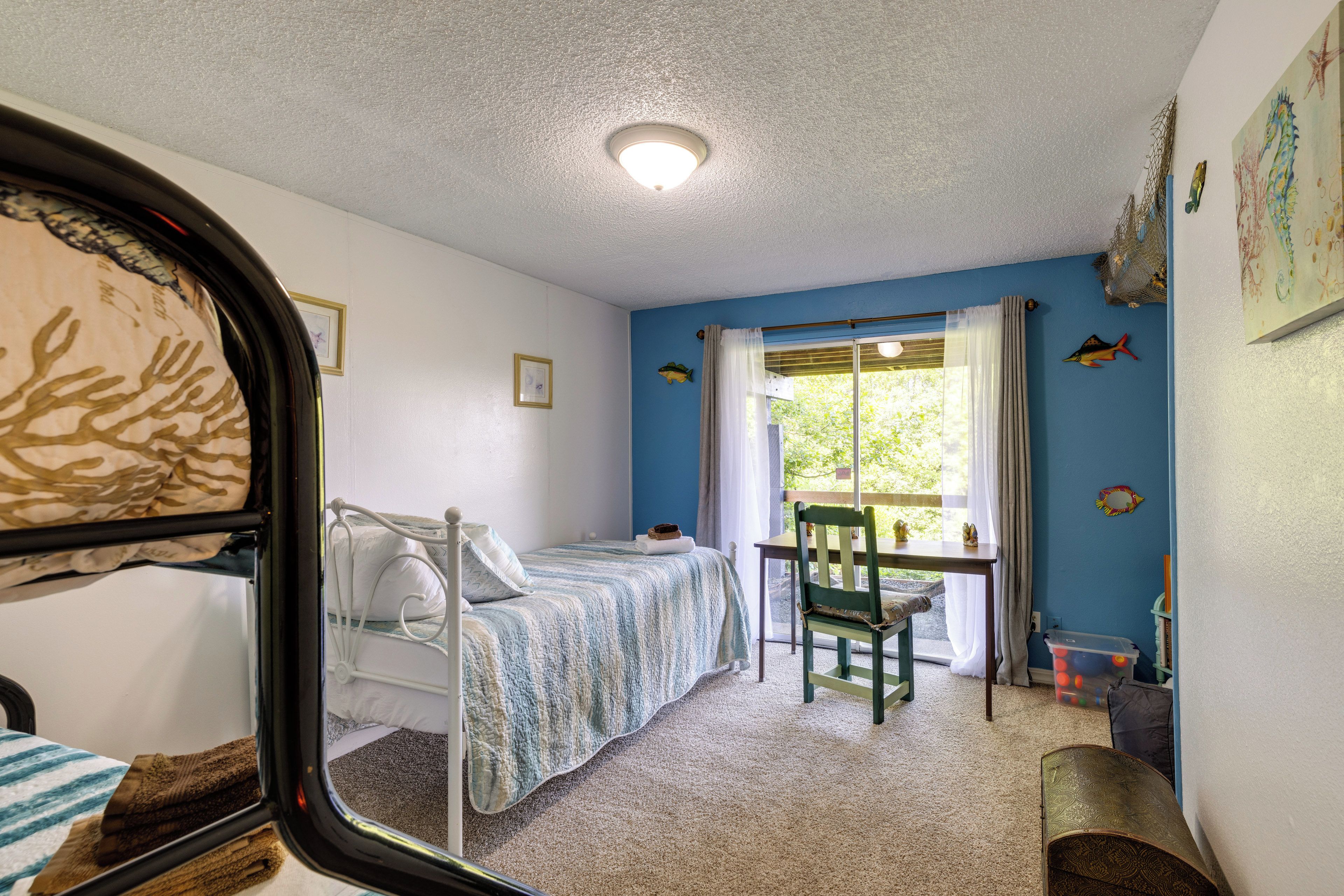 A room with a bunk bed, a desk with a chair, and a window with curtains.