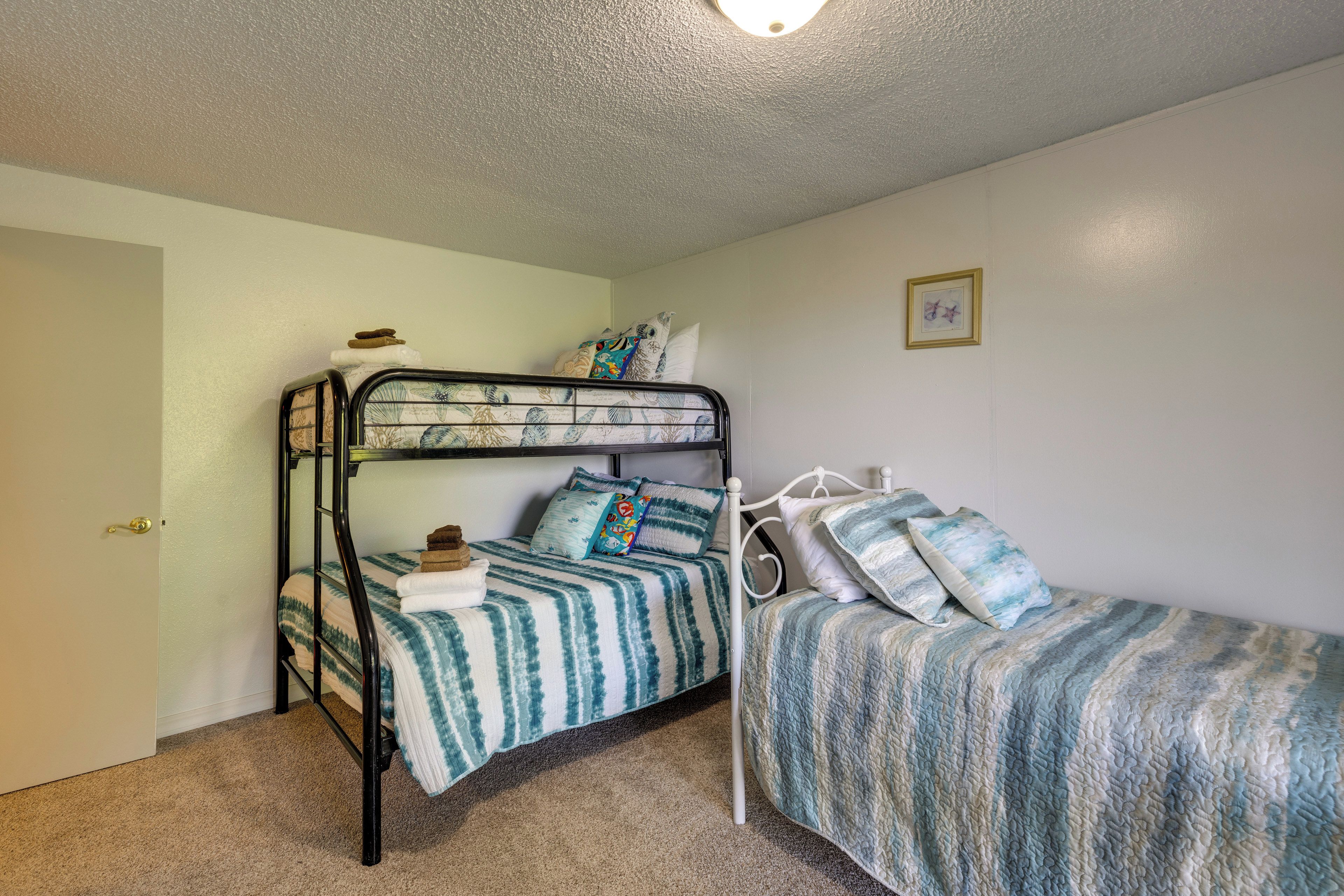 A bunk bed room with a door, a framed picture on the wall, and a carpeted floor.