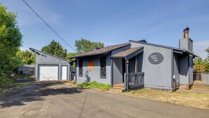 Een tweelaags gebouw met een garage, schoorsteen en een bord waarop staat 