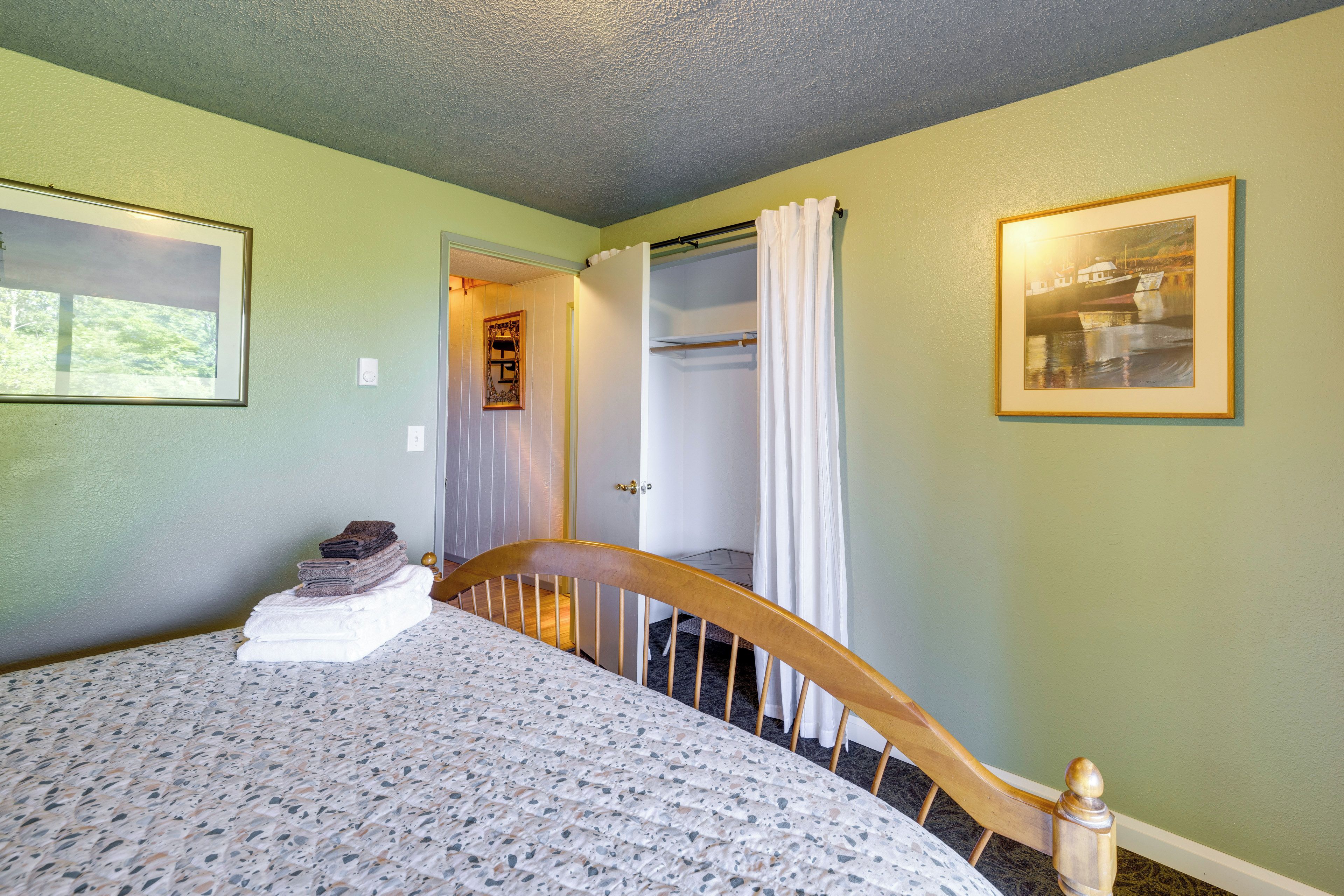 Une chambre à coucher avec un lit, une porte donnant sur un placard, un tableau encadré au mur et une fenêtre.