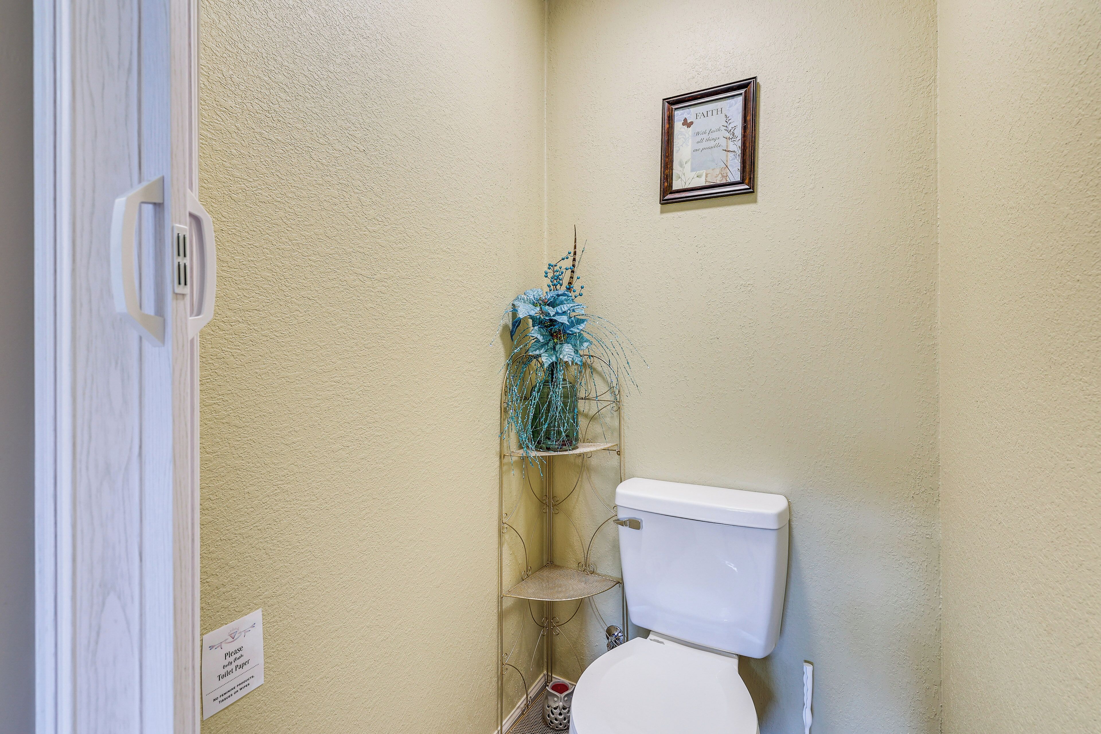 Een badkamer met een toilet, een plankje met een decoratieve plant en een bord met een raamwerk aan de muur.