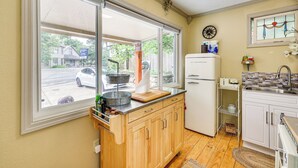 A compact kitchen with a large window, a refrigerator, and a sink. - Eureka Springs Rental - Walk to Downtown! (Eureka Springs)