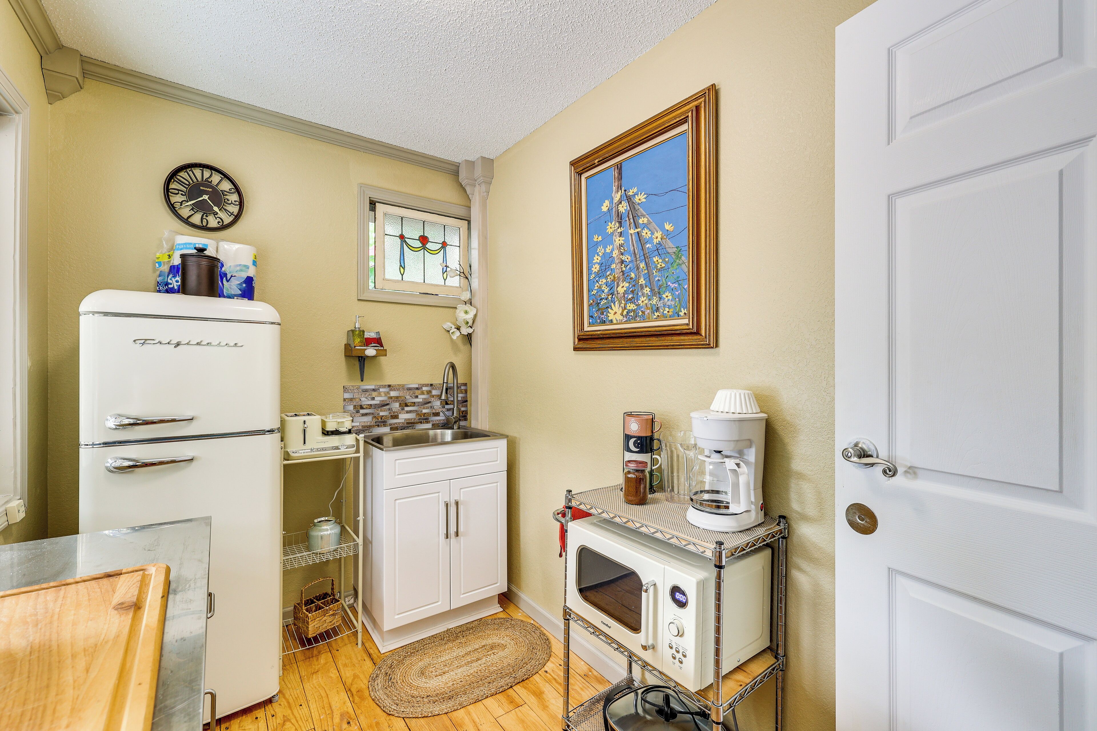 A compact kitchen with a refrigerator, microwave, and coffee maker on a cart.
