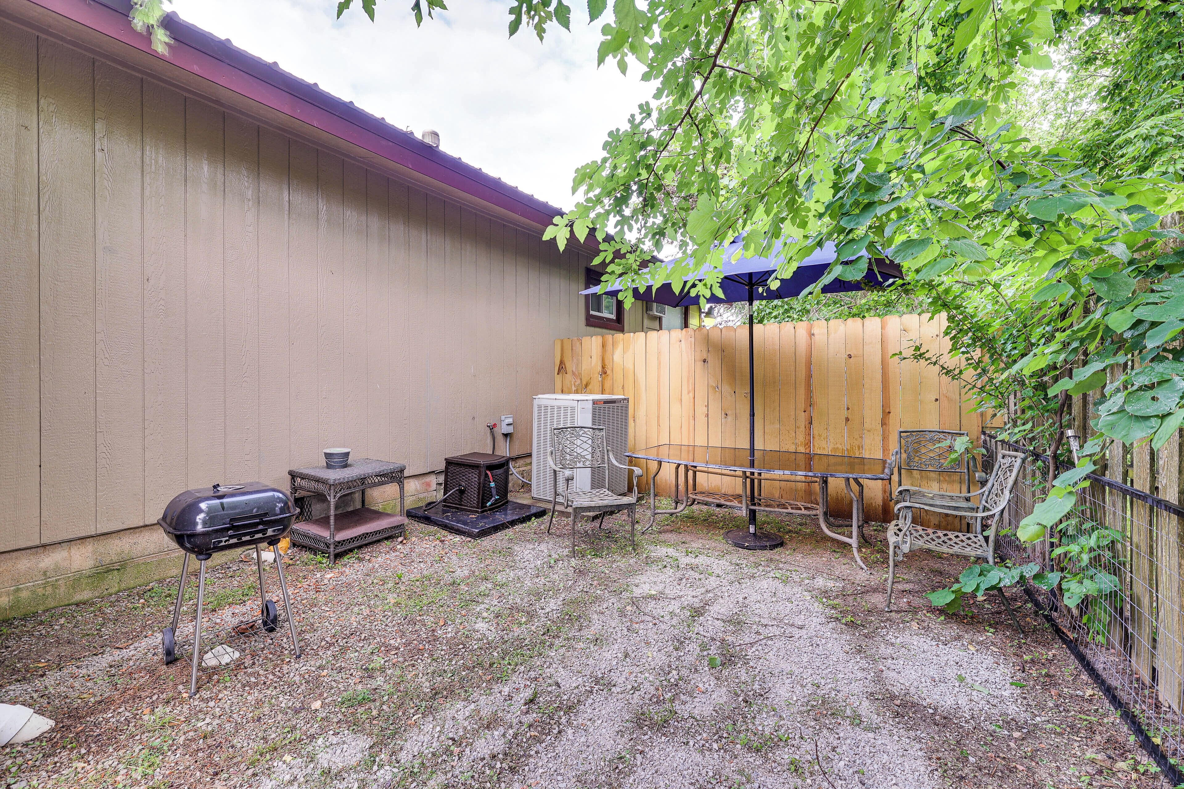 Un jardin avec un barbecue, du mobilier d’extérieur et une clôture en bois.