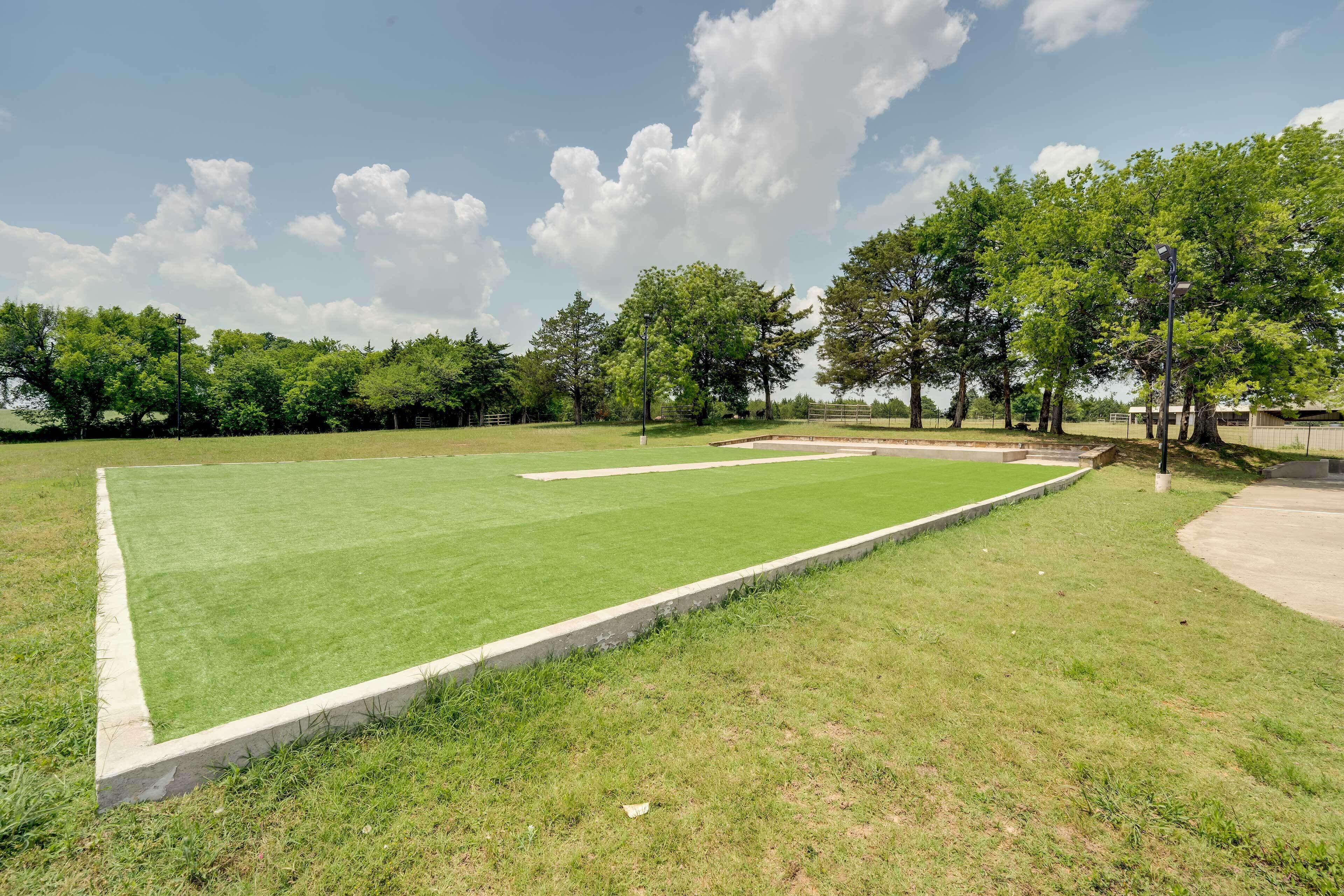 A well-maintained lawn with a concrete border, surrounded by trees and a clear sky.