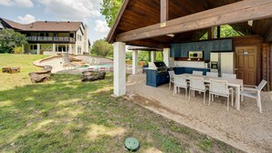 A covered outdoor area with a barbecue setup, seating, and a pool.