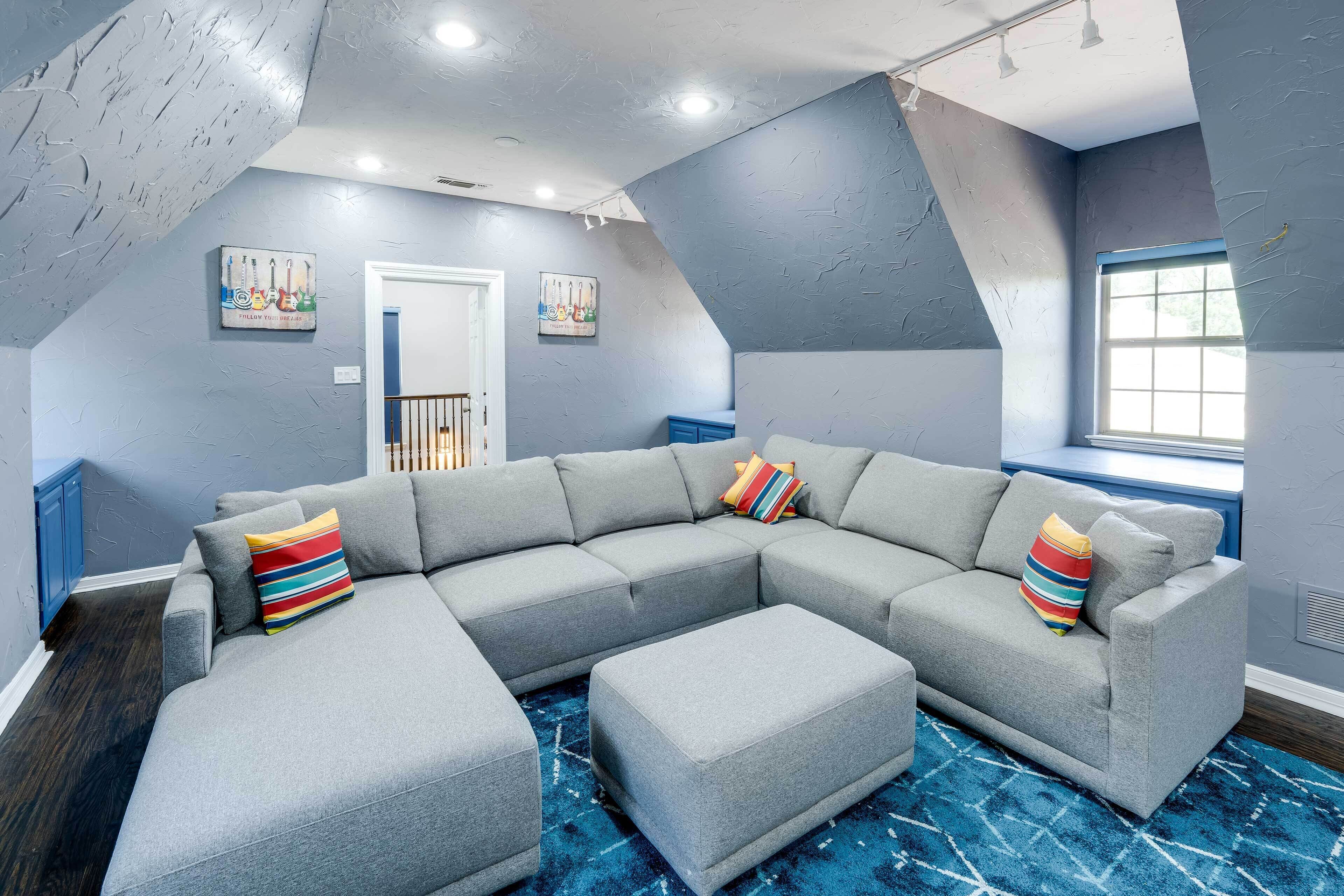 A modern living room with a sectional sofa, a blue patterned rug, and a window with a view.