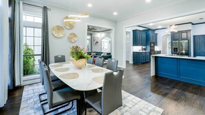A modern kitchen with dark wood flooring, a central island, and blue cabinetry.