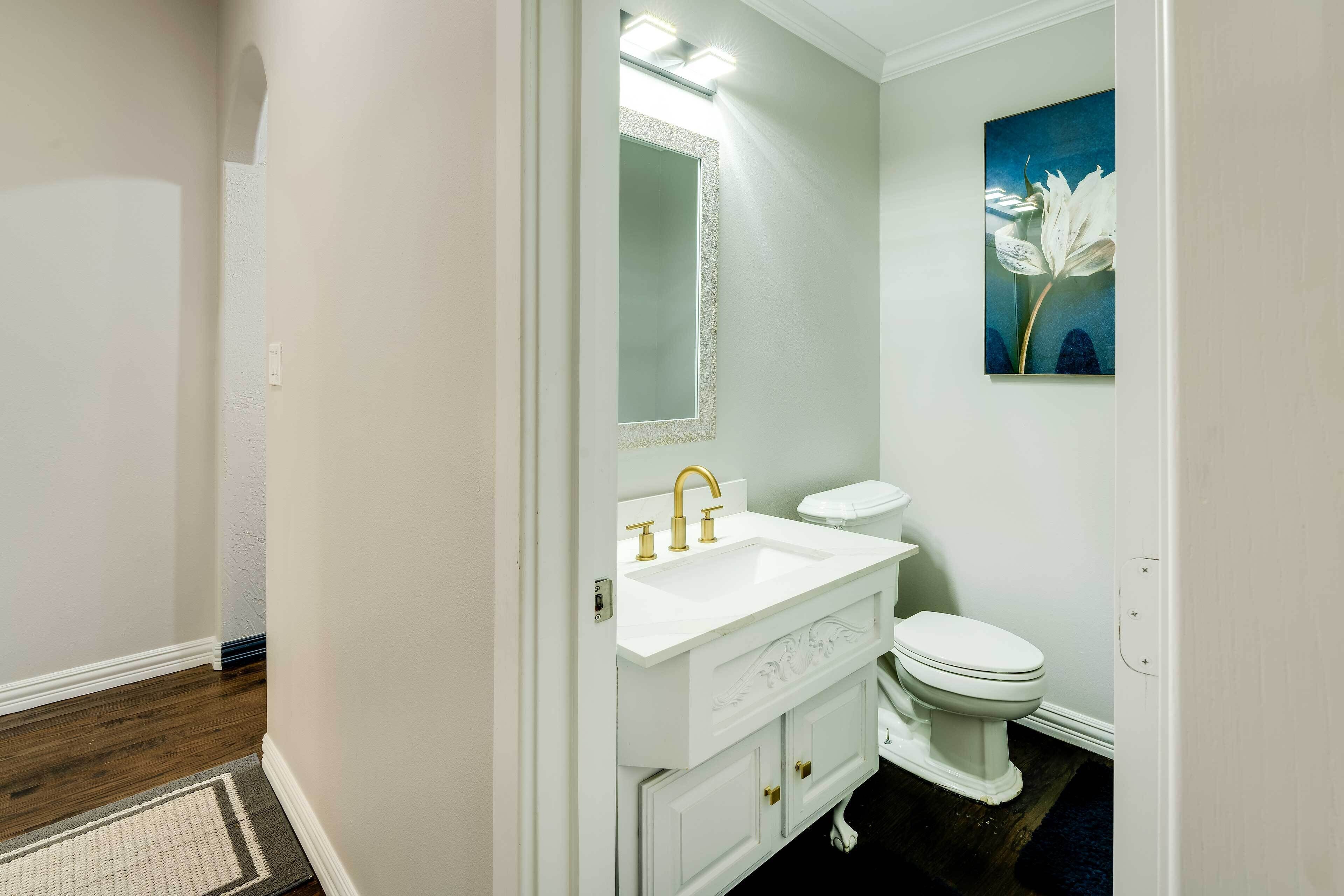 A bathroom with a white sink, vanity, and toilet.