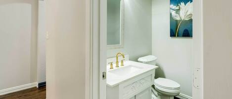 A bathroom with a white sink, vanity, and toilet.