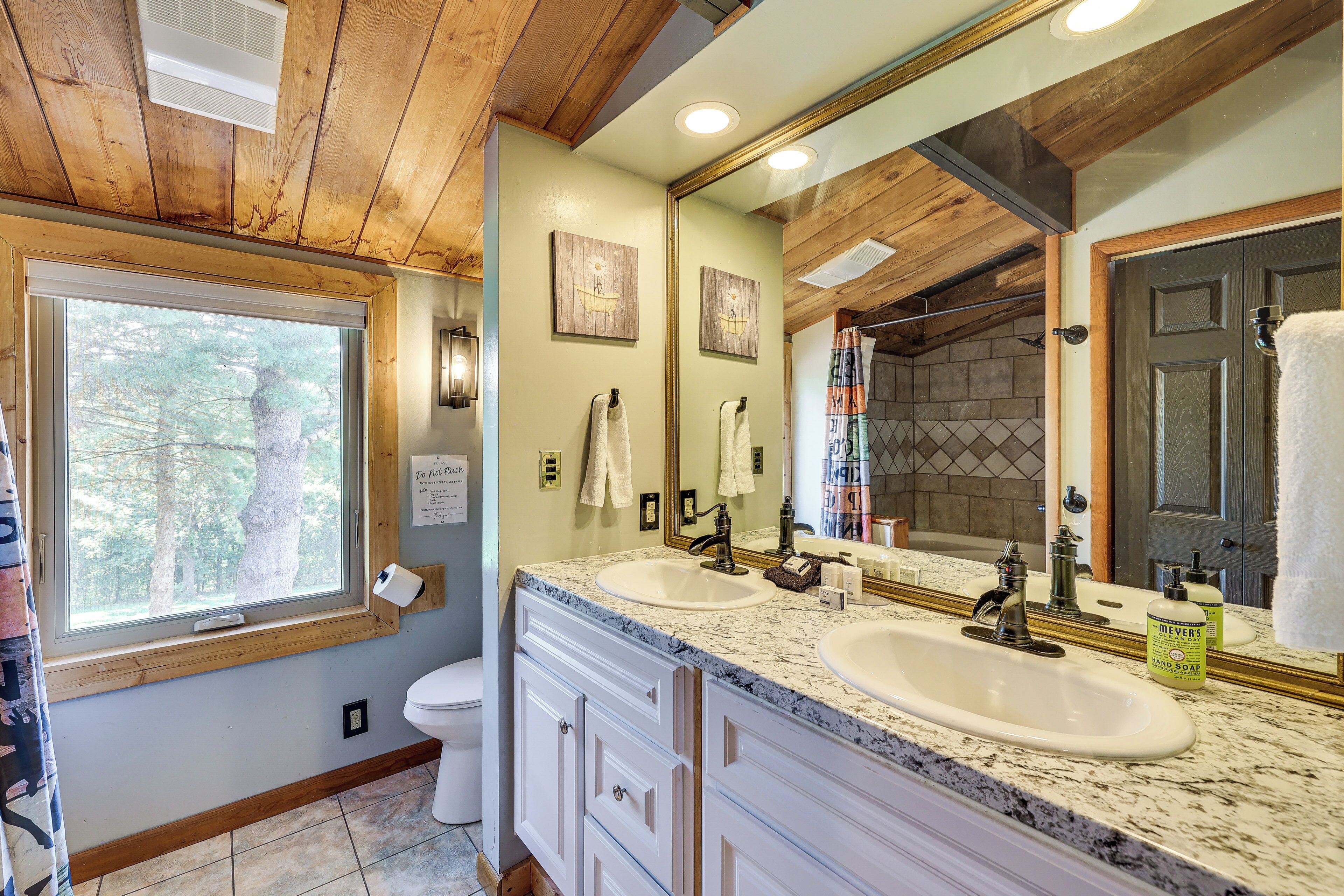 A bathroom with two sinks, wooden ceiling, and a large mirror.