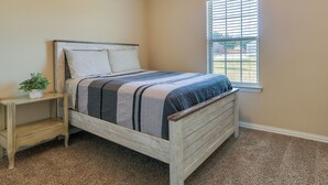 A bedroom with a wooden bed, a nightstand, a window with blinds, and a carpeted floor. - ~ 10 Mi to Dtwn Mckinney: Home w/ Patio & Yard (McKinney)