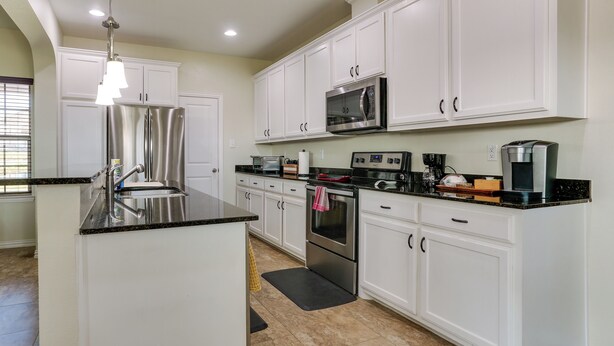 A modern kitchen with white cabinets, stainless steel appliances, and a black countertop. - ~ 10 Mi to Dtwn Mckinney: Home w/ Patio & Yard (McKinney)