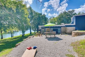 A lakeside picnic area with a wooden bench, picnic table, and a covered seating area. - Kimberling City Home: Boat Slip & Lakefront Bliss! (Kimberling City)