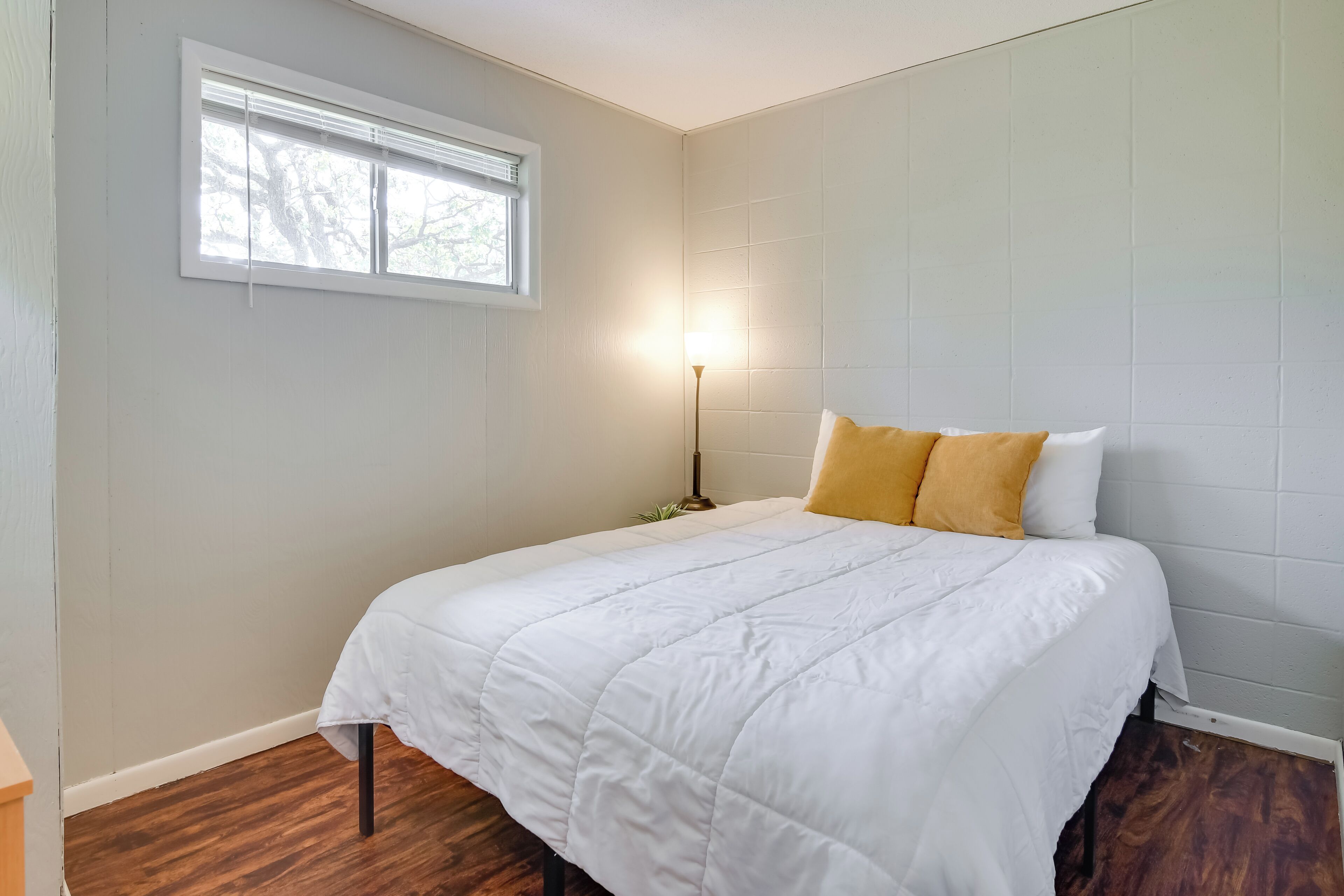 A bedroom with a bed, a window, and a floor lamp.